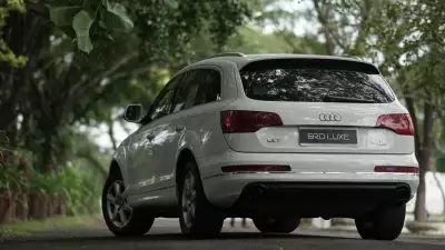White luxury Audi Q7 driving down a forested road