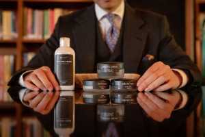 A person in a suit and tie sitting at a table with shoe lotions and creams