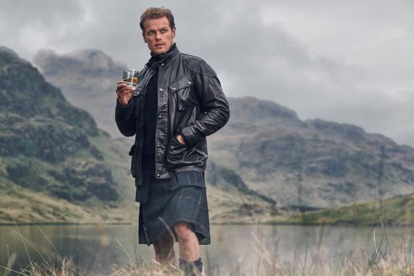 Sam Heughan holding a glass of Sassenach whisky