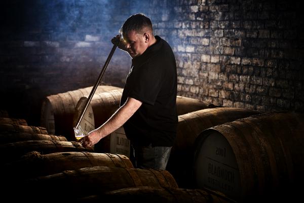 Sampling the spirit from the barrel with a whisky thief