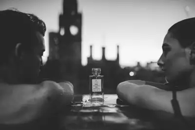 Two people in a pool between a bottle of fragrance