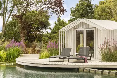 Sun loungers by water feature in contemporary garden