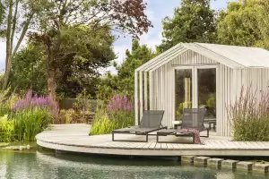 Sun loungers by water feature in contemporary garden