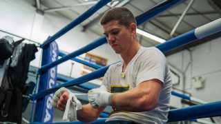 Luke Campbell strapping boxing glove in gym