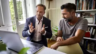 Men discussing finance at a computer