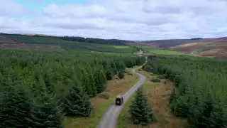 Land Rover Defender 110s driving through Kielder Forest
