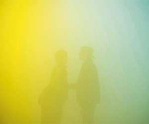 Couple standing in Ann Veronica Janssen's Yellowbluepink light installation