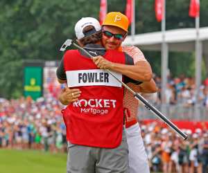 PGA golfer Rickie Fowler gets a hug from his caddie Ricky Romano on the 18th green after winning in a 3 way playoff on July 2, 2023, during the final round of the Rocket Mortgage Classic at the Detroit Golf Club in Detroit, Michigan.