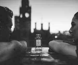 Two people in a pool between a bottle of fragrance