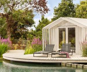 Sun loungers by water feature in contemporary garden